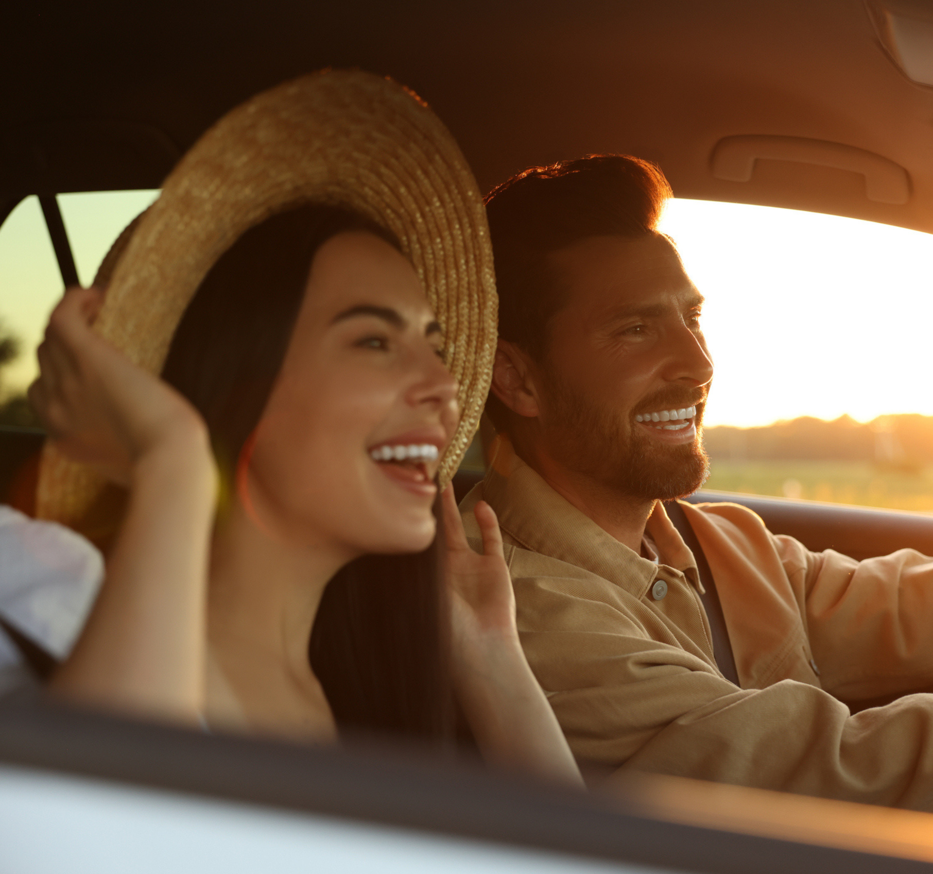 Man and woman laughing as they drive in the car on a roadtrip.